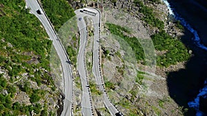 Aerial view of coach bus cautiously making a sharp turn on Trollstigen or Trolls Path, a popular narrow serpentine mountain road.