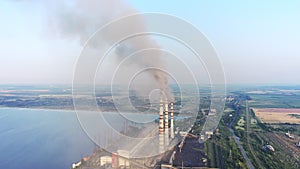 Aerial view of coal power plant high pipes with black smokestack polluting atmosphere.