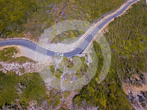 Aerial view of the coast of Corsica, winding roads. Cyclists running on a road. France