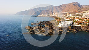 Aerial view of coastal resort town of Tenerife Island. Cityscape of Puerto de Santiago del Teide holidays homes on rocky