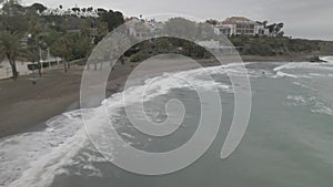 Aerial view of the coastline with slashing waves in Malaga on a gloomy day