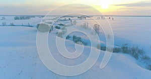 Aerial view of cold arctic field landscape, trees with frost snow, ice river and sun rays over horizon. Extreme low