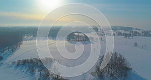 Aerial view of cold winter landscape arctic field, trees covered with frost snow, ice river and sun rays over horizon