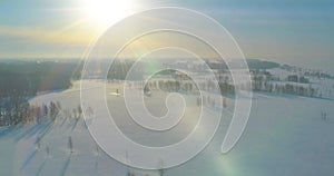 Aerial view of cold winter landscape arctic field, trees covered with frost snow, ice river and sun rays over horizon