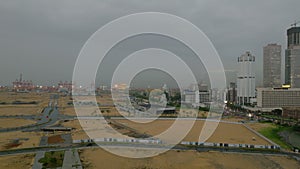 Aerial view of Colombo City Port at rainy dusk. Modern tall buildings and massive cranes in harbour in background