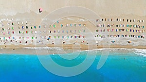 Aerial view of colorful chaise lounges deck chairs on the beach of the turquoise sea.