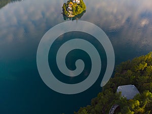 Aerial view of the colorful forest and Lake Bled with a small island with a church. Sunrise in Slovenia in the fall. Castle, aeria