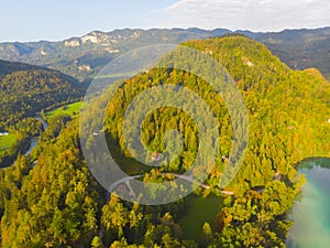 Aerial view of the colorful forest and Lake Bled with a small island with a church. Sunrise in Slovenia in the fall. Castle, aeria