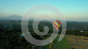 An aerial view of a colorful hot air balloon flying over the rice fields.