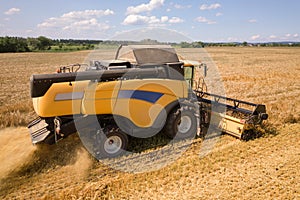 Aerial view of combine harvester harvesting large ripe wheat field. Agriculture from drone view