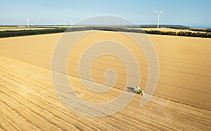 Aerial view of combine harvester harvesting wheat. Beautiful wheat field at sunset