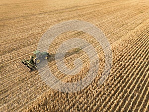 Aerial view on the combine working on the large corn field. Haymaking and harvesting in early autumn on the field. Tractor mows