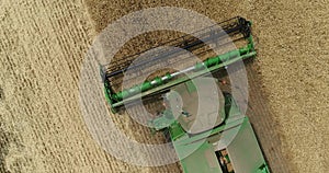 Aerial view on the combines and tractors working on the large wheat field, Harvester on the wheat field, Green harvester