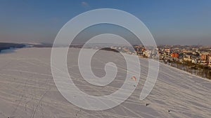 Aerial view. Competitions pilots of the paraglider on a frozen lake near the city park at sunset of the day