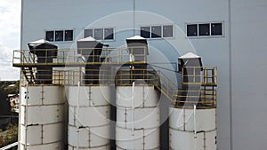Aerial view of concrete mixing plant and four tanks. Stock footage. Flying over cement storage silos, industrial
