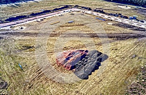 Aerial view of a construction site for the development of a new housing area with the road substructure in the back and mounds of