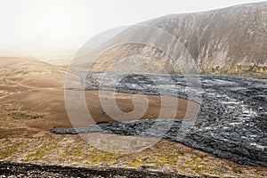 Aerial view of cooled down black volcanic lava rocks and red soil in Icelandic highlands near Geldingadalir volcano