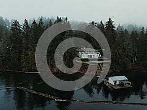 Aerial view of a cottage house on a cliff with pine trees near Sproat Lake