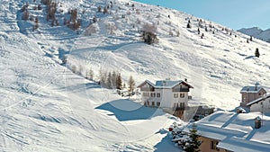 Aerial view of cottages and chalets in ski resort in the ski area of Madesimo and Valchiavenna and snowy slopes, alpine