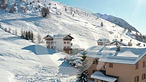 Aerial view of cottages and chalets in ski resort in the ski area of Madesimo and Valchiavenna and snowy slopes, alpine