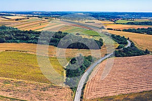 Aerial view of a country road amid fields against blue clear sky