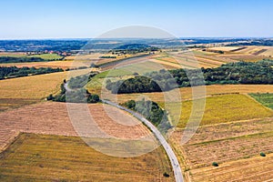 Aerial view of a country road amid fields against blue clear sky
