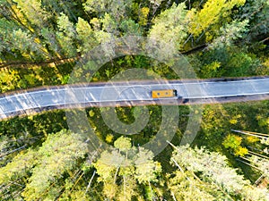 Aerial view of a country road in the forest with moving cars. Beautiful landscape. Captured from above with a drone. Aerial bird`