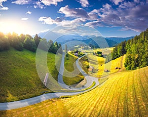 Aerial view of country road in green meadows at sunset in summer