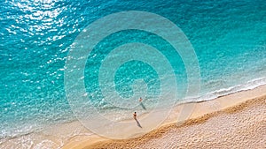 Aerial view of couple standing in beautiful sandy beach with soft turquoise ocean wave. Tropical sea in summer season on Porto