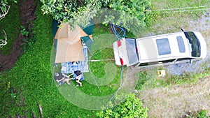 Aerial view of couples sit in front of the tent and are holding