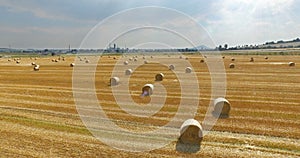 Aerial view of cropped wheat field with bales of hay in the countryside. View of the highway with driving lorryes on a