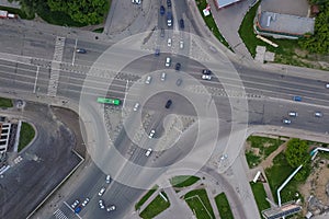 Aerial view of crossed road, crossroads, car traffic and crosswalk with white stripes in the city among the green trees. Russian