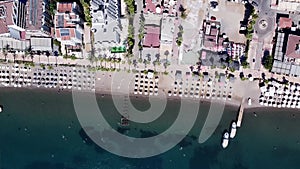 Aerial view of a crowded beach with umbrellas, people swimming in the sea, sunny day. Drone view of beach with white