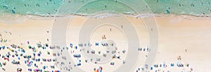 Aerial view crowded public beach with colourful umbrellas, Aerial view of sandy beach with tourists swimming in beautiful clear