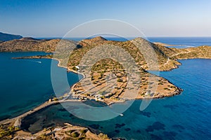Aerial view of the crystal clear ocean and dry summer coastline of Kolokitha and Olous near Elounda, Crete, Greece
