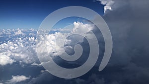 Aerial view of cumulus cloudscape from airplane window against blue sky