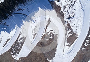 Aerial view of the curving alpine skiing and snowboarding piste