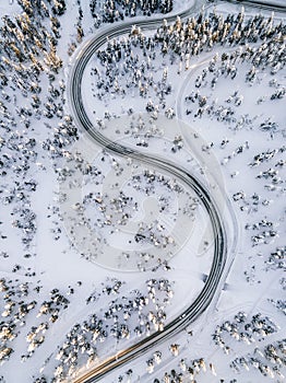 Aerial view of Curvy Windy Road in snow covered forest in Winter Finland