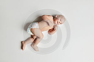 Aerial view of cute infant, little child baby toddler wearing nappy lying on floor with happy facial expression over