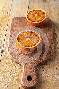 Aerial view of cutting board with two orange halves, on rustic table