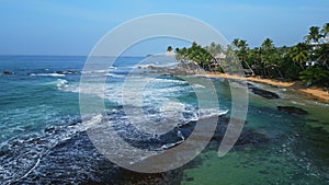 Aerial view of Dalawella beach with turquoise waters, tourists swimming, palm trees lining shore, sandy beach, coastal