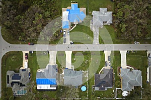 Aerial view of damaged in hurricane Ian house roof covered with blue protective tarp against rain water leaking until