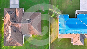 Aerial view of damaged in hurricane Ian house roof covered with blue protective tarp against rain water leaking until