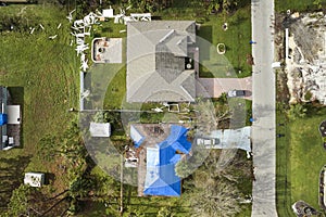 Aerial view of damaged in hurricane Ian house roof covered with blue protective tarp against rain water leaking until