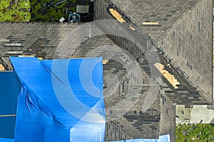 Aerial view of damaged in hurricane Ian house roof covered with blue protective tarp against rain water leaking until