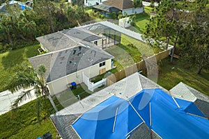 Aerial view of damaged in hurricane Ian house roof covered with blue protective tarp against rain water leaking until