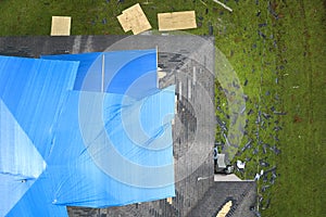 Aerial view of damaged in hurricane Ian house roof covered with blue protective tarp against rain water leaking until