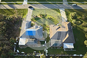 Aerial view of damaged in hurricane Ian house roof covered with blue protective tarp against rain water leaking until