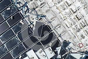 Aerial view of damaged by hurricane wind photovoltaic solar panels mounted on industrial building roof for producing