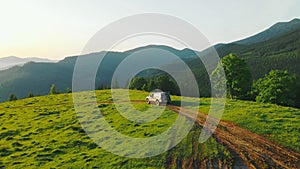 Aerial view of dawn in the highlands. The SUV is standing on a dirt road in the mountains. Hiking in the mountains